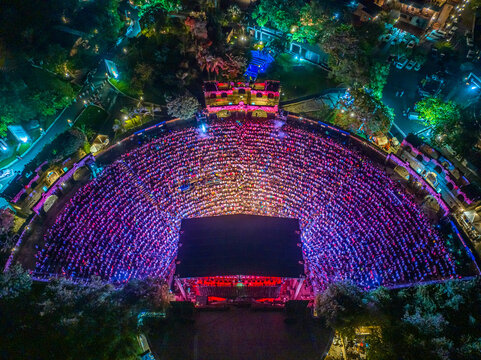 Aerial view of the Altos de Chavon Amphitheatre at night, filled with a large crowd attending a concert, illuminated by stage lights in La Romana, La Romana, Dominican Republic.