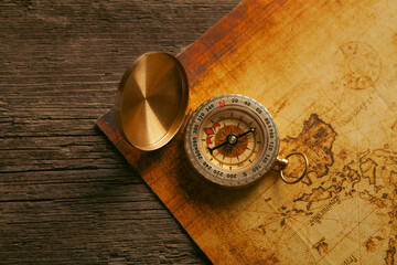 Compass and old map on wooden background. Vintage style toned picture © Artvibe