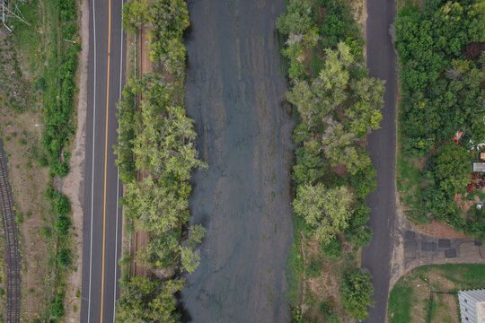 Aerial view of a river flowing through a lush green landscape with a road running parallel and dense trees lining the banks in Englewood, Colorado, United States.
