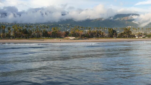 Santa Barbara, California coastline as seen from Stearns Wharf on a sunny afternoon after rain, January 2024. Waves and clouds among the Santa Ynez mountains in the background.