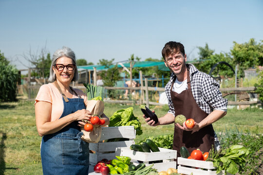Two happy farmers selling fresh organic vegetables and fruits from their garden