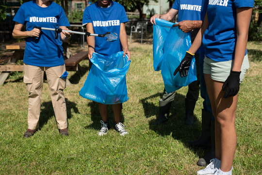 Group of volunteers wearing blue volunteer shirts, collecting trash in blue bags