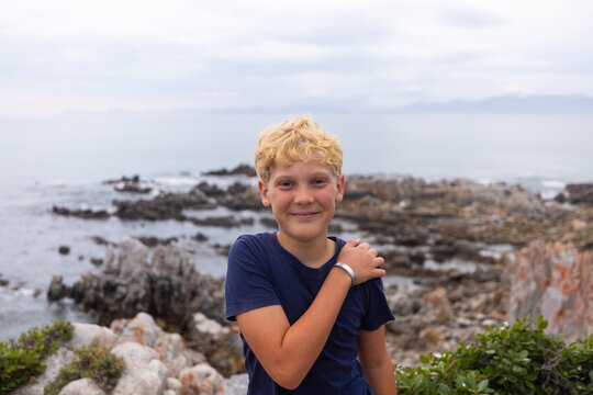 smiling boy in stormy late afternoon light on rocky coastline of DeKelders, South Africa
