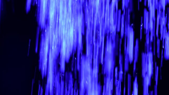 Tiny snow or dust randomly flying in the smoky air, empty space template for objects advertisement. Many dust particles cloud of white powder in blue light on empty dark black contrast background.