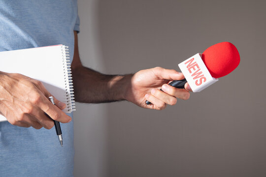 Journalist holding a microphone and notepad.