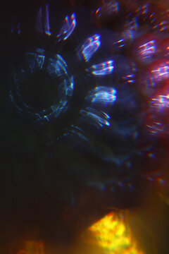 Abstract light patterns with vibrant colors and shapes. The image features kaleidoscopic effect with circular and linear designs.