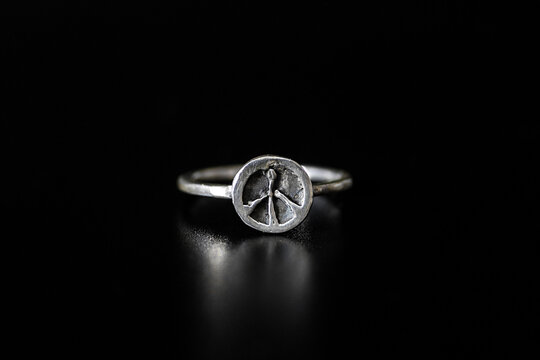 Silver ring featuring a peace symbol on a black background. The ring has a simple design and a polished finish, emphasizing the peace motif.