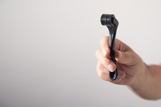 Male hand holding a derma roller.