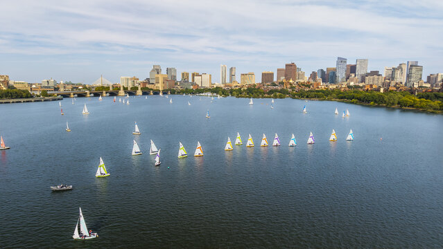 Aerial view of sailboats racing on the Charles River with the Boston skyline in the background under a clear blue sky in Cambridge, Massachusetts, United States.