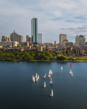 Aerial view of sailboats on the Charles River with the Boston skyline and Prudential Tower in the background under a blue sky in Boston, Massachusetts, United States.