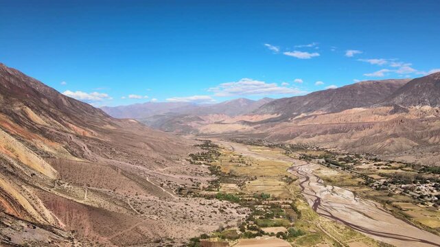 Wide drone shot from Cerro General San Mart&iacute;n of the R&iacute;o Grande valley, dry riverbed and patchwork farms framed by multicolored mountains at Paleta del Pintor.