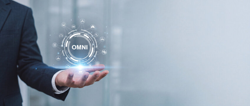 Businessman hand holding glowing OMNI channel icon for integrated retail marketing, digital transformation, and unified business technology solutions in a modern corporate environment.