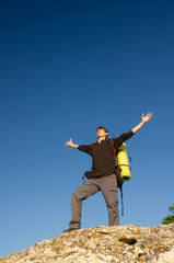 A young hiker with a backpack stands on a cliff © Nemeziya