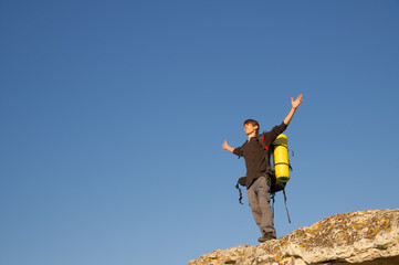 A young hiker with a backpack stands on a cliff © Nemeziya