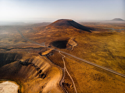 Aerial view of Lake Meke, a volcanic crater and distant cinder cones, surrounded by arid landscape and dry terrain in Karapinar, Konya, Turkiye.