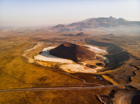 Aerial view of Lake Meke, a volcanic crater lake with a central cone surrounded by arid plains and distant mountains in Karapinar, Konya, Turkiye.