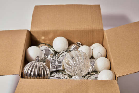 Cardboard Box Filled with Silver and White Christmas Ornaments and Baubles