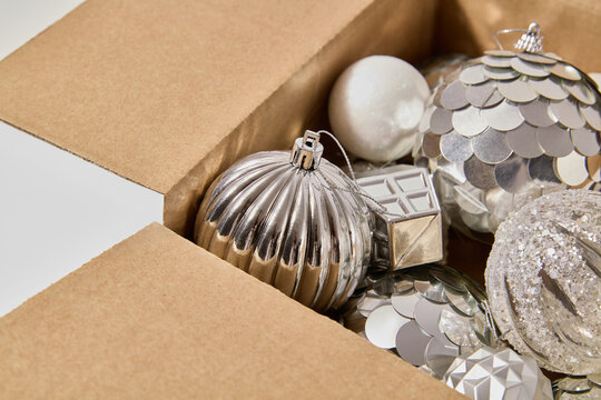 Cardboard box packed with shiny silver Christmas baubles and holiday decorations