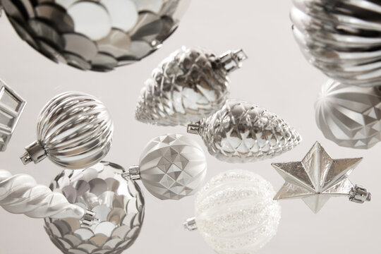 Silver and white Christmas tree ornaments floating against bright background