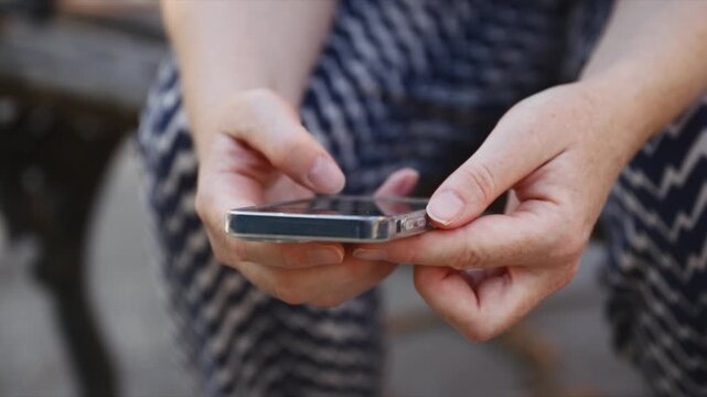 Woman using a smartphone with both hands in a close-up lifestyle scene. Mobile technology, online communication, messaging, browsing and everyday digital connectivity concept. 4K.