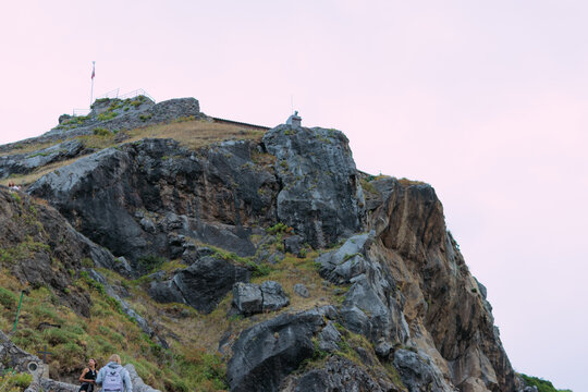 Tourists hiking up mount srd, a rocky historic hill featuring fortifications and a flag on its summit, overlooking the scenic landscape of dubrovnik, croatia