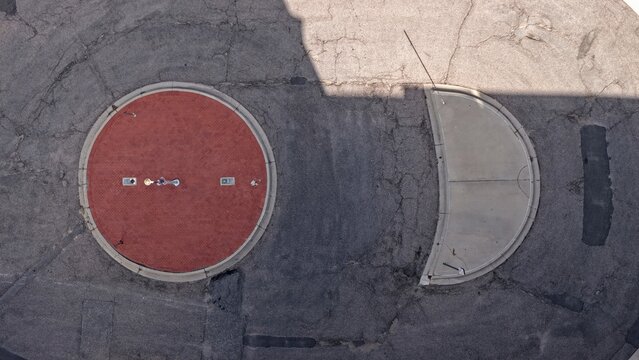Aerial view of a circular red brick plaza and a semi-circular concrete section set within an asphalt parking lot in Denver, Colorado, United States.