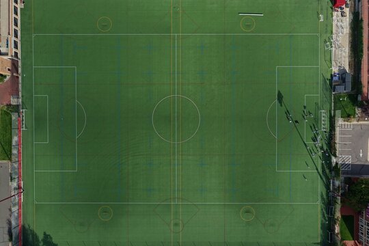 Aerial view of a green sports field with white markings and players on the sidelines in Denver, Colorado, United States.