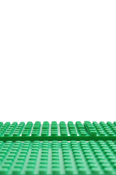 Green LEGO baseplates stacked and arranged on a reflective surface with black background.