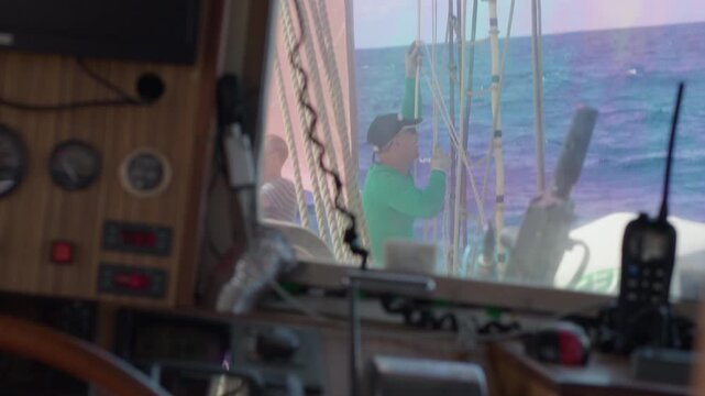 Crew work with the sails on the big expeditional sailing vessel moving in the Atlantic Ocean