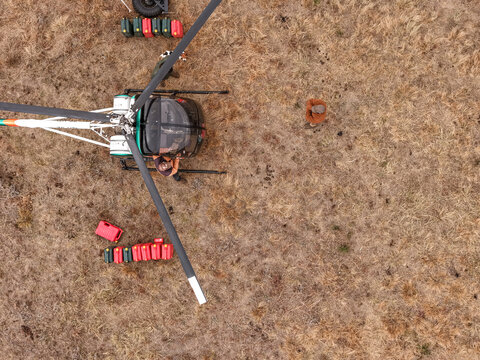 Aerial view of a wildlife veterinarian preparing veterinary drugs beside a helicopter during a wildlife management operation on dry savanna in Vaalwater, Limpopo, South Africa.