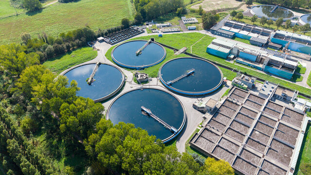 Aerial view of Depuratore di Peschiera Borromeo featuring large circular sedimentation tanks and rectangular treatment basins in Peschiera Borromeo, Lombardia, Italy.