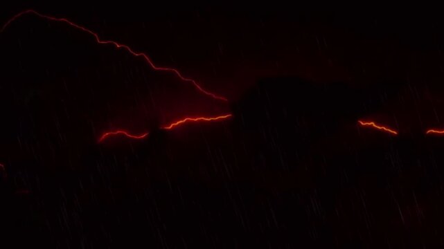 Heavy rain falling with dramatic red and yellow lightning strikes flashing in a stormy night sky
