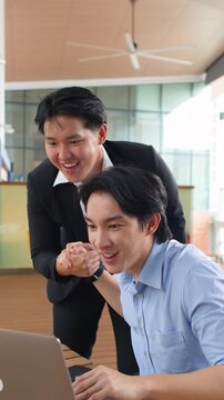 Two Asian Businessmen Celebrating Success with Handshake in Office