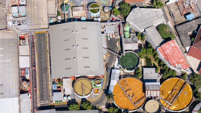 Aerial view of an industrial water treatment facility with large circular processing tanks, metal rooftops, and complex piping systems in Salatiga, Central Java, Indonesia.