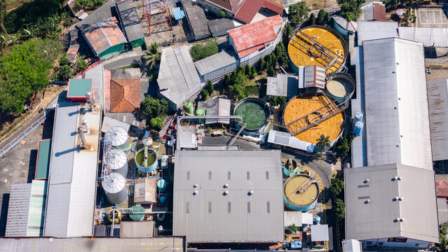 Aerial view of an industrial facility featuring large circular processing tanks, metal rooftops, and storage silos in Salatiga, Central Java, Indonesia.