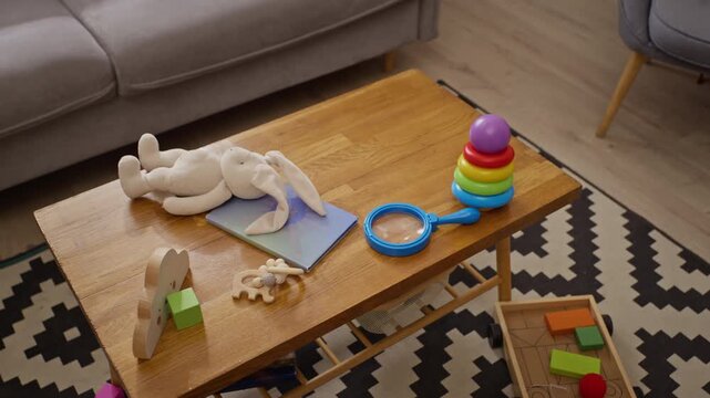 Colorful toddler toys, plush bunny, educational stacking rings resting on wooden table from high angle view. Ideal for parenting campaigns, child development, early learning advertisements