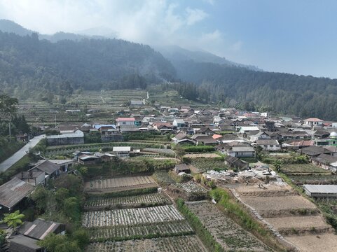 Aerial view of the terraced agricultural fields and village houses near Merbabu View and Cafe, set against the misty slopes of Mount Merbabu in Kecamatan Getasan, Jawa Tengah, Indonesia.