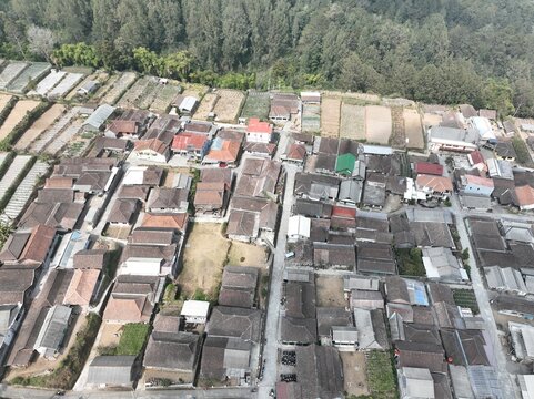 Aerial view of a dense village with traditional tiled rooftops, narrow streets, and surrounding agricultural fields in Kecamatan Getasan, Jawa Tengah, Indonesia.