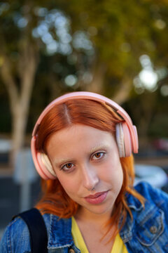 Woman with bleached eyebrows and nose piercing enjoying audio content, expressing youth and individuality