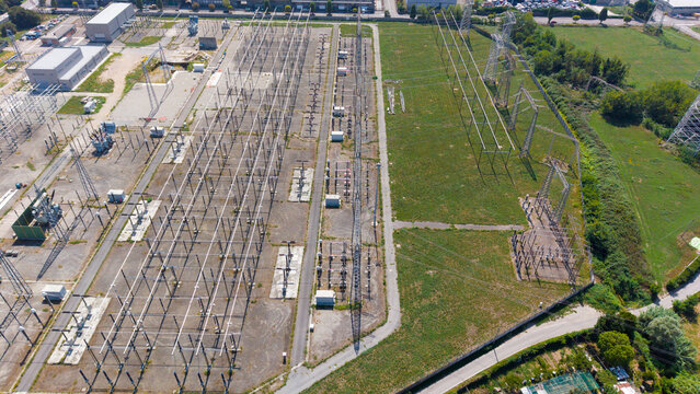 Aerial view of Stazione Elettrica Terna Baggio featuring metal power grid structures, transformers, and electrical infrastructure in grassy fields in Settimo Milanese, Lombardia, Italy.