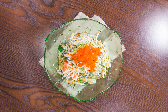 Fresh vegetable salad with fish roe on a wooden table in a casual dining setting