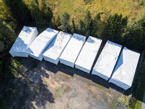 Aerial view of prefabricated houses wrapped in white protective plastic sheeting arranged in a row in Kempele, North Ostrobothnia, Finland.