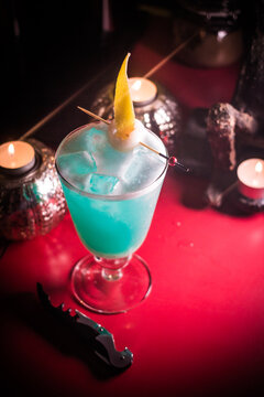 Colorful cocktail served on a table with candles at a bar during the evening