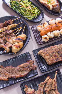 Grilled food served on black plates at a dining table in an indoor restaurant