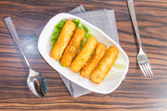Fried snacks served on lettuce with forks and spoons on wooden table