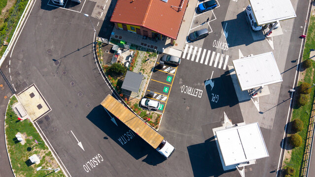 Aerial view of Eni petrol and electric filling station with fuel pumps, charging bays, and a truck parked in the forecourt in San Giuliano Milanese, Lombardy, Italy.