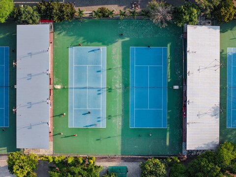 Aerial view of Manahan Echowave Tennis Courtyard featuring blue courts with green surroundings, white lines, and players in Surakarta, Central Java, Indonesia.