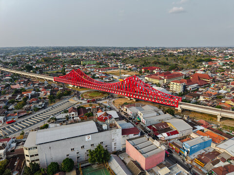 Aerial view of the red steel Jembatan Kereta Api Joglo railway bridge spanning across the urban landscape of Surakarta, Jawa Tengah, Indonesia.