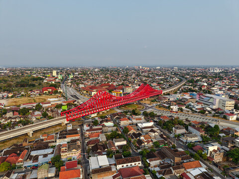 Aerial view of Jembatan Kereta Api Joglo, a prominent red railway bridge spanning over the urban landscape of Surakarta, Jawa Tengah, Indonesia.