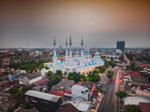 Aerial view of Sheikh Zayed Grand Mosque Solo with its white domes and minarets surrounded by the urban landscape of Surakarta, Central Java, Indonesia.